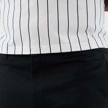 New Era Black Cargo Shorts, front view on a model, displaying the black fabric with belt loops at the waistband and tailoring, styled with a white shirt featuring slim black vertical pinstripes.
