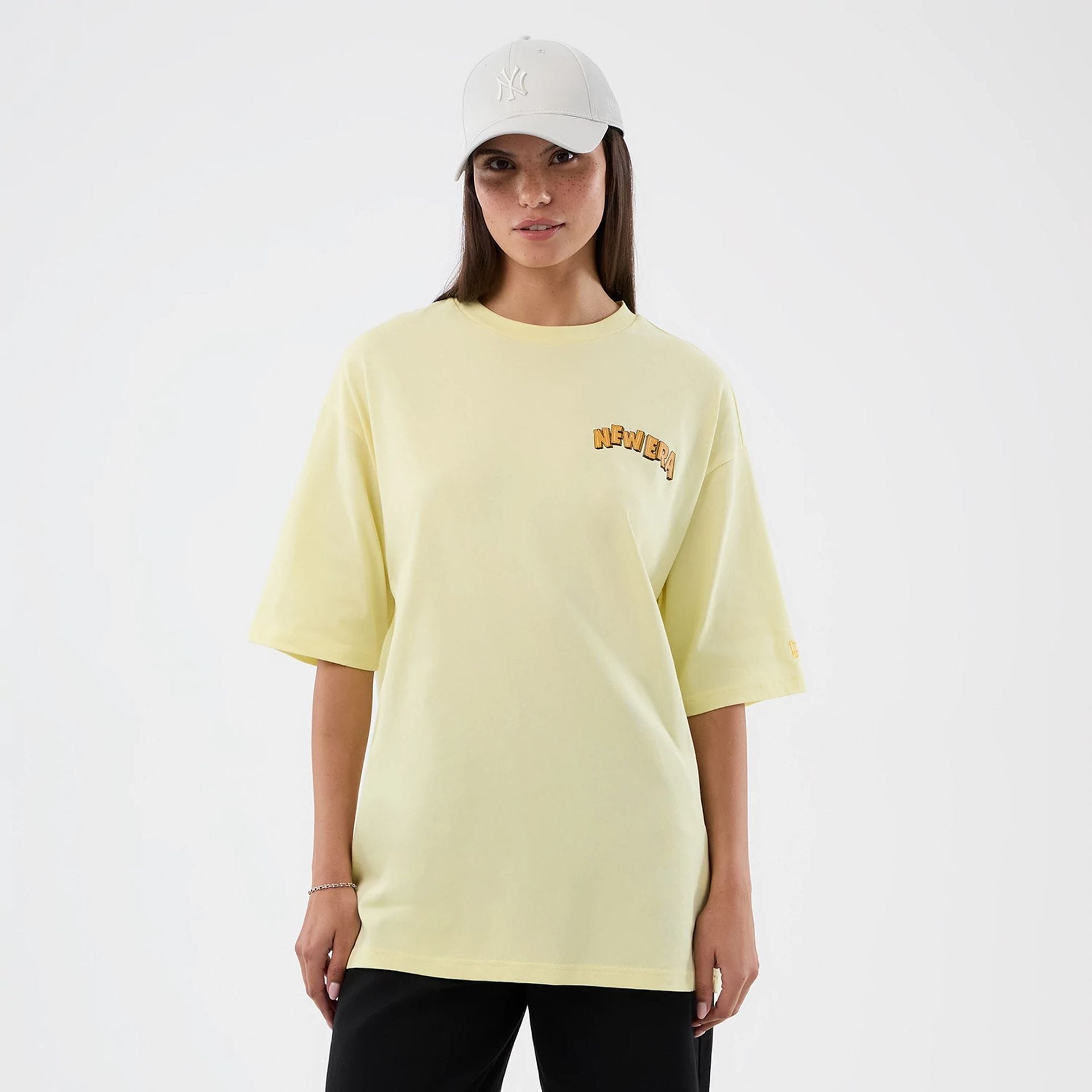 The model is wearing this New Era Fun Beach Party Graphic Oversized T-Shirt in pastel yellow. 4