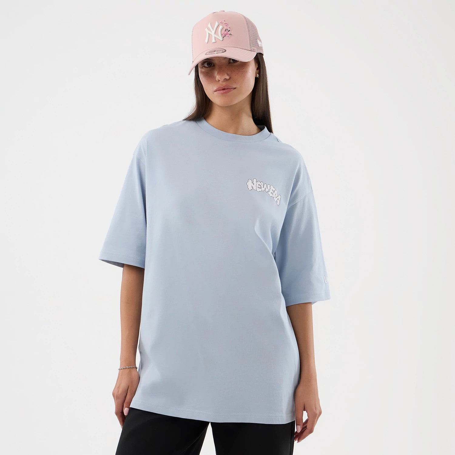 The model is wearing this New Era Fun Block Party Graphic Oversized T-Shirt in pastel blue. 4