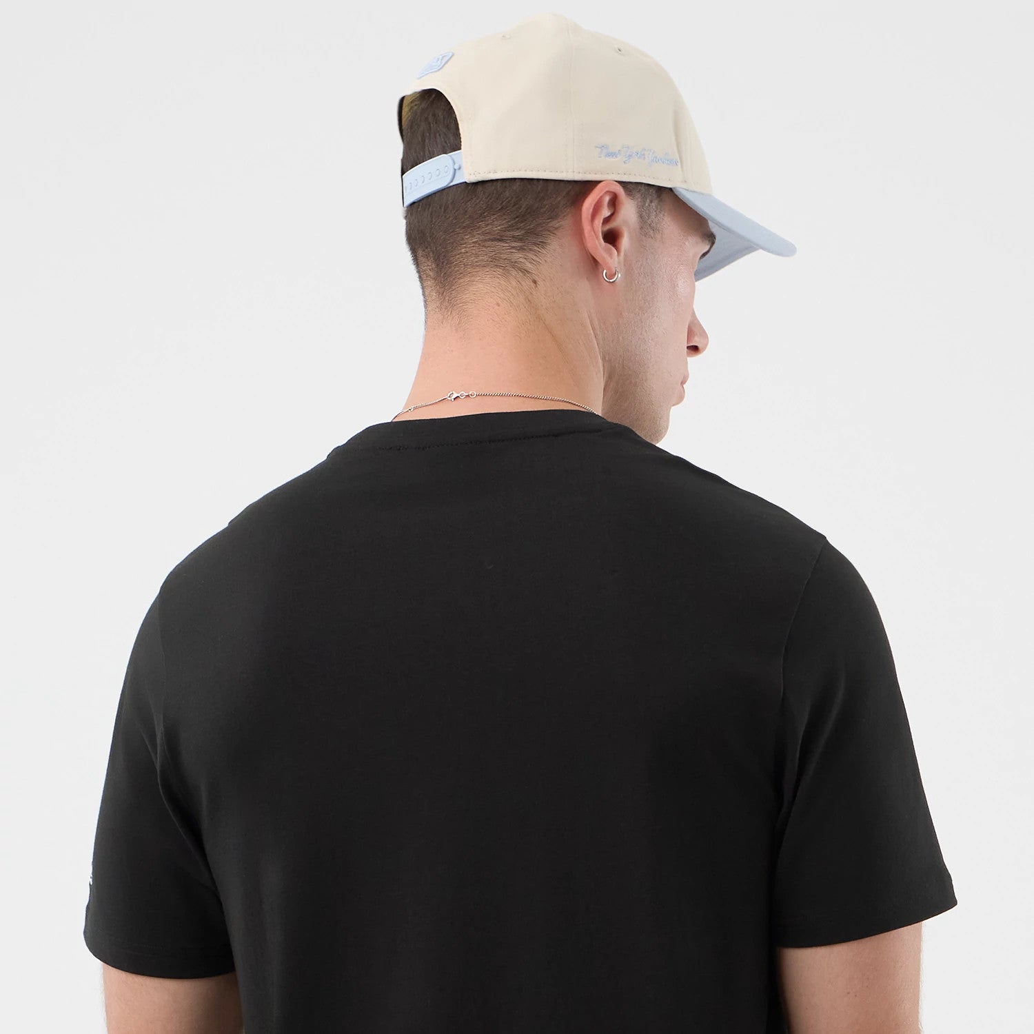 The model is wearing this New Era Logo Graphic T-Shirt in black. 7