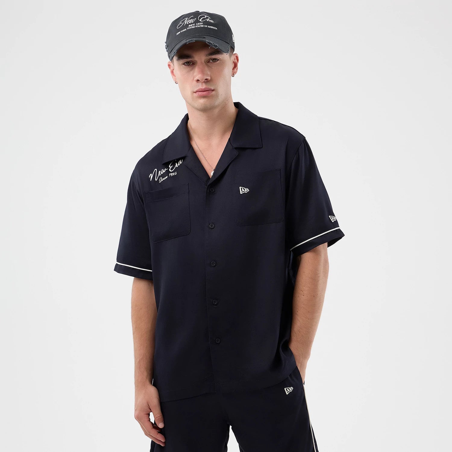 The model is wearing this New Era Graphic Revere Short Sleeve Shirt in navy. 3