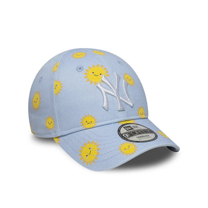 New York Yankees Toddler MLB Summer Pastel Blue New Era 9FORTY Adjustable Cap, three-quarter view showing a white raised embroidered NY logo on the front panel, a pattern of smiling yellow suns, and a 9FORTY size sticker on the curved visor.