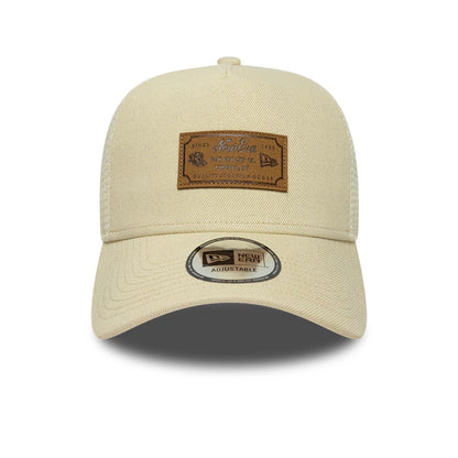 Pictured is this New Era Leather Patch 9FORTY A-Frame Trucker cap in light beige. 2