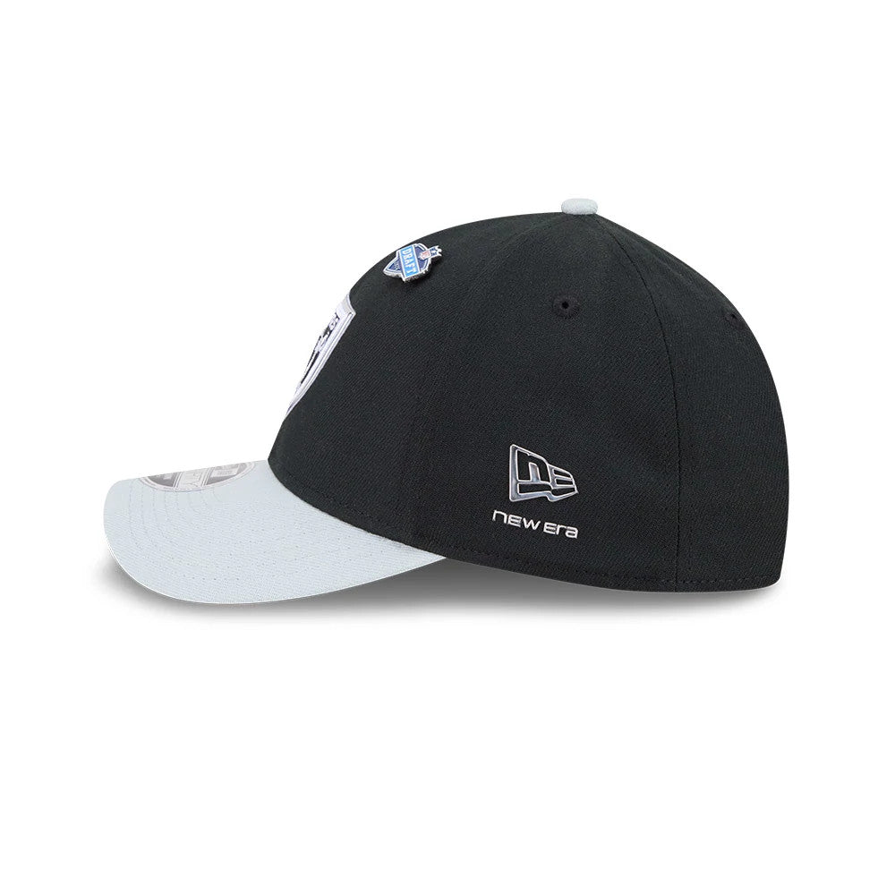 Raiders NFL Draft 2026 Black New Era 39THIRTY M-Crown Stretch Fit Cap, side view showing the silver embroidered New Era flag logo on the black structured crown, with light grey curved visor and a draft pin attached near the eyelet.