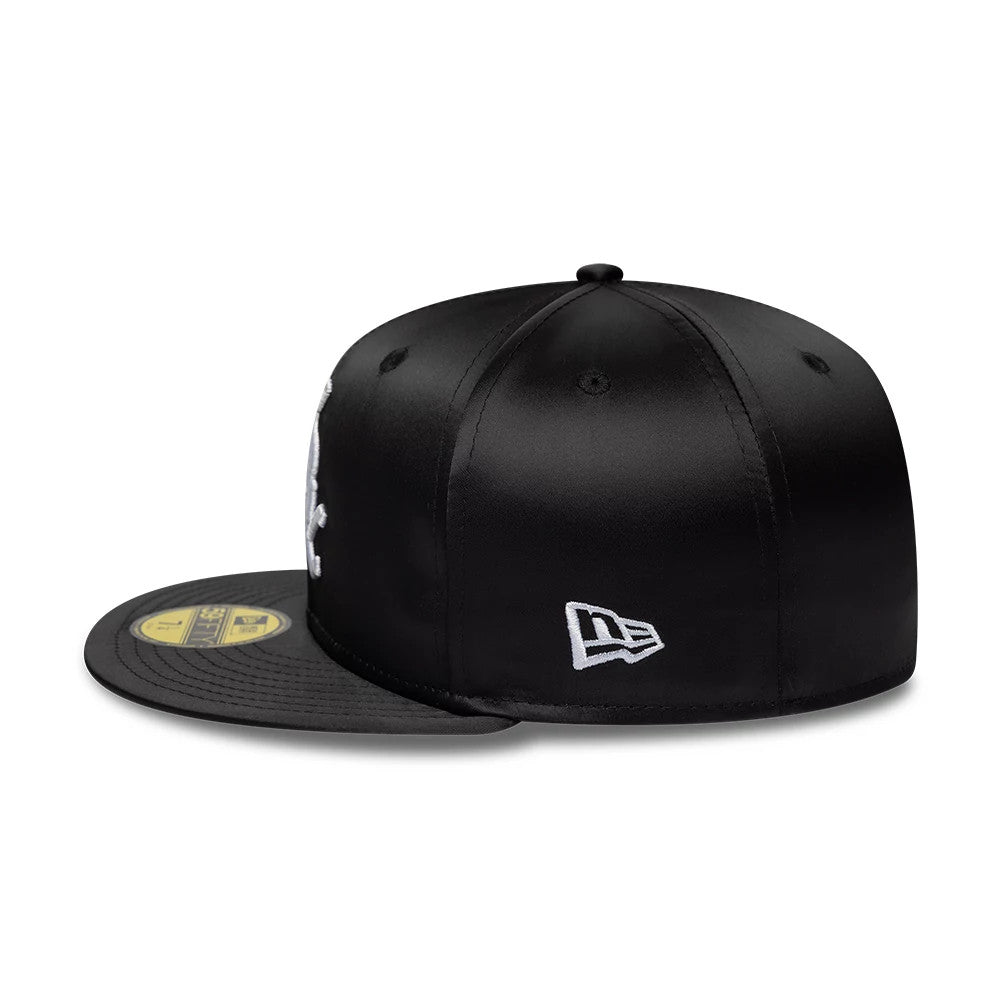 Chicago White Sox MLB Satin Black New Era 59FIFTY Fitted Cap, side view showing the embroidered New Era flag logo on the black satin fabric, structured crown and flat black visor with a gold 59FIFTY size sticker on top.