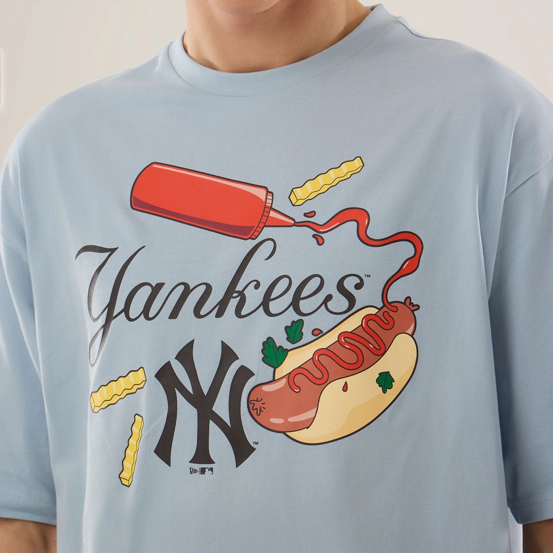 The model is wearing this MLB Food Graphic New York Yankees Oversized T-Shirt in pastel blue. 3