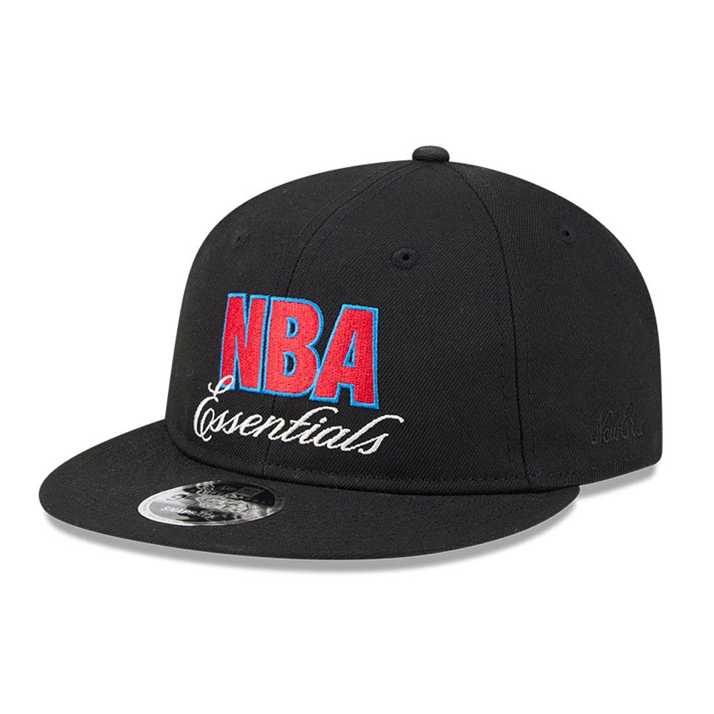 FOG x NBA Logo Black Retro Crown New Era 9FIFTY Snapback Adjustable Cap, three-quarter view showing red and blue embroidered NBA Essentials lettering on the front panel, with a flat black visor and a 9FIFTY size sticker on top.