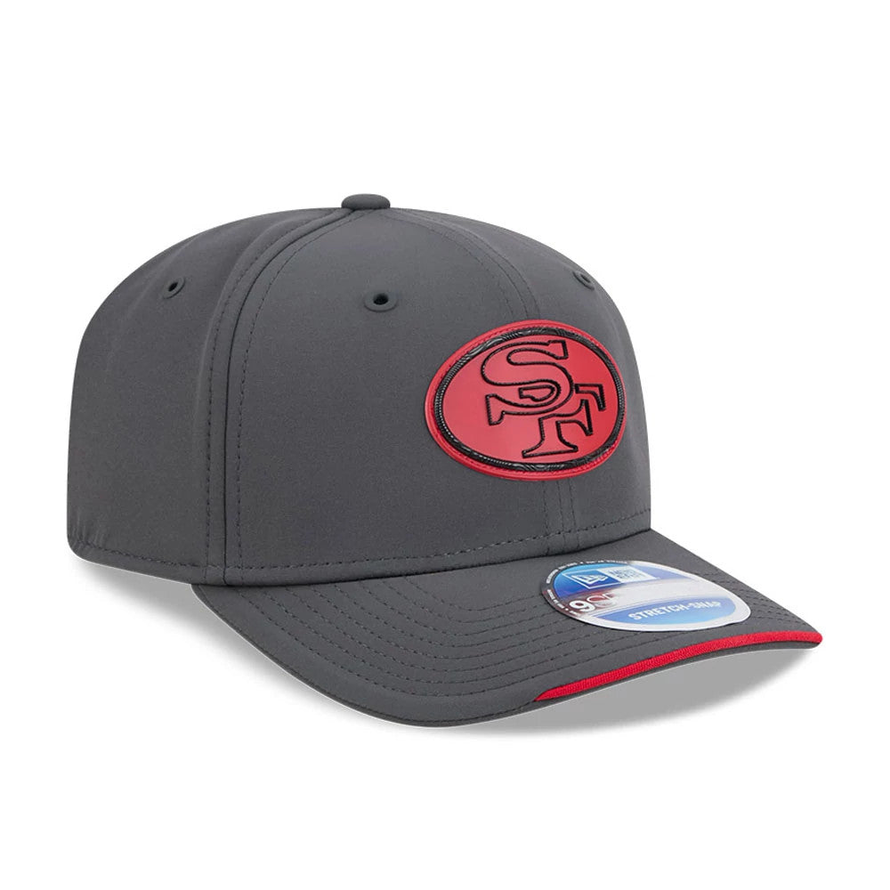 49ers NFL Sideline 2026 Charcoal New Era 9SEVENTY Stretch Snap Adjustable Cap, three-quarter view showing the raised red SF logo on the front panel, a dark charcoal curved visor with red trim, and the blue 9SEVENTY size sticker on top.