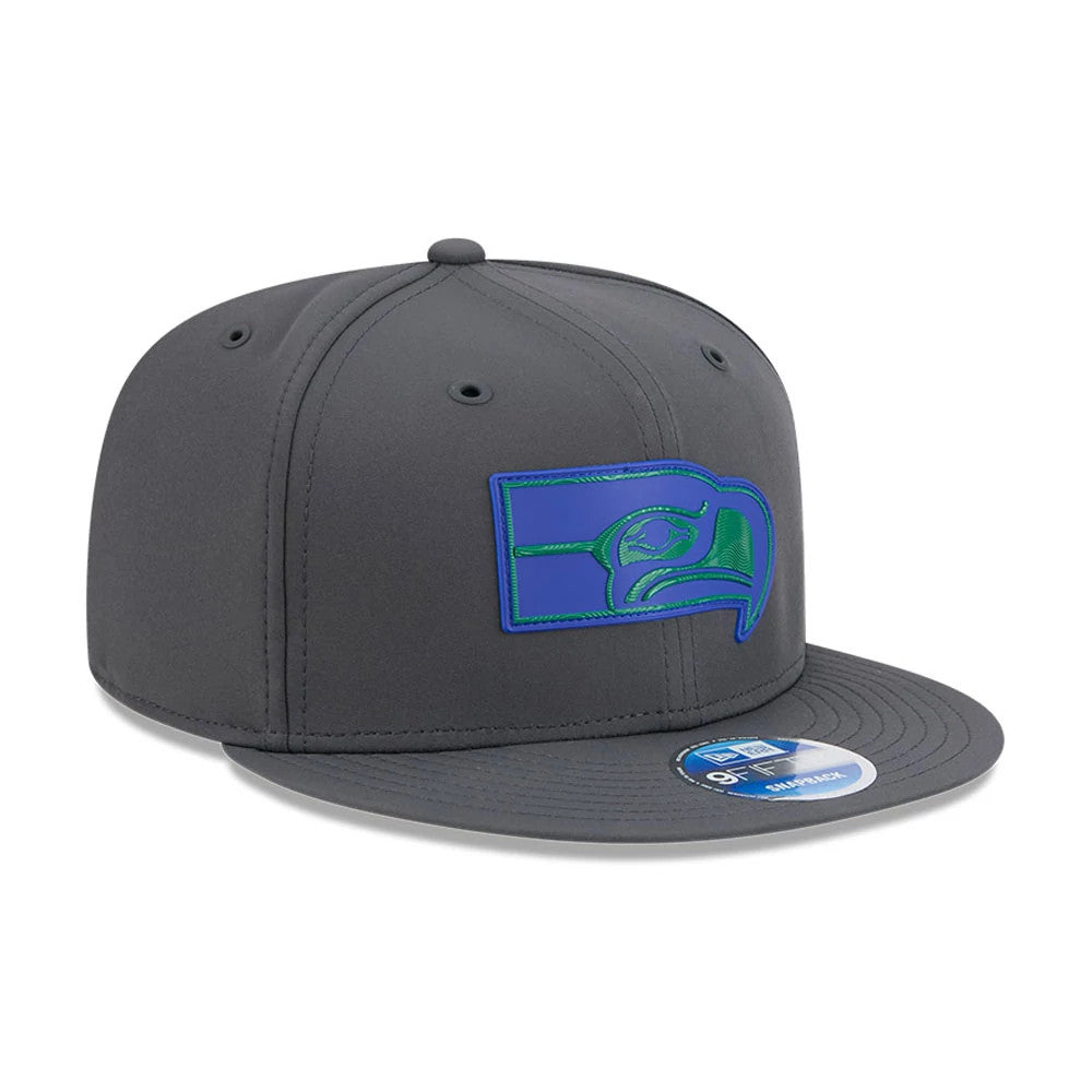 Seahawks NFL Sideline 2026 Charcoal New Era 9FIFTY Snapback Adjustable Cap, three-quarter view showing the raised blue and green embroidered Seahawks logo on the front panel, grey flat visor with an undervisor, and 9FIFTY size sticker.