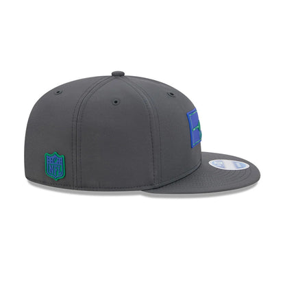 Seahawks NFL Sideline 2026 Charcoal New Era 9FIFTY Snapback Adjustable Cap, side view showing the blue and green New Era logo on the left panel, grey flat visor, and the embroidered NFL shield logo at the centre back.