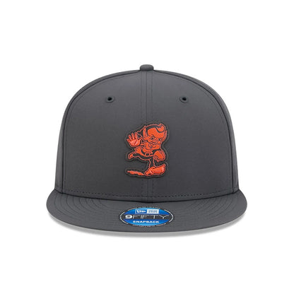 Browns NFL Sideline 2026 Charcoal New Era 9FIFTY Snapback Adjustable Cap, front view showing the flat charcoal visor, a prominent orange embroidered mascot logo on the front panel, and a 9FIFTY size sticker on the visor.