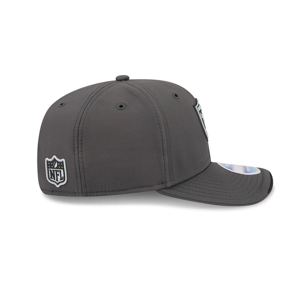 Raiders NFL Sideline 2026 Charcoal New Era 9SEVENTY Stretch Snap Adjustable Cap, side view showing the black and white NFL shield logo on the left side, the charcoal structured crown with black eyelets.