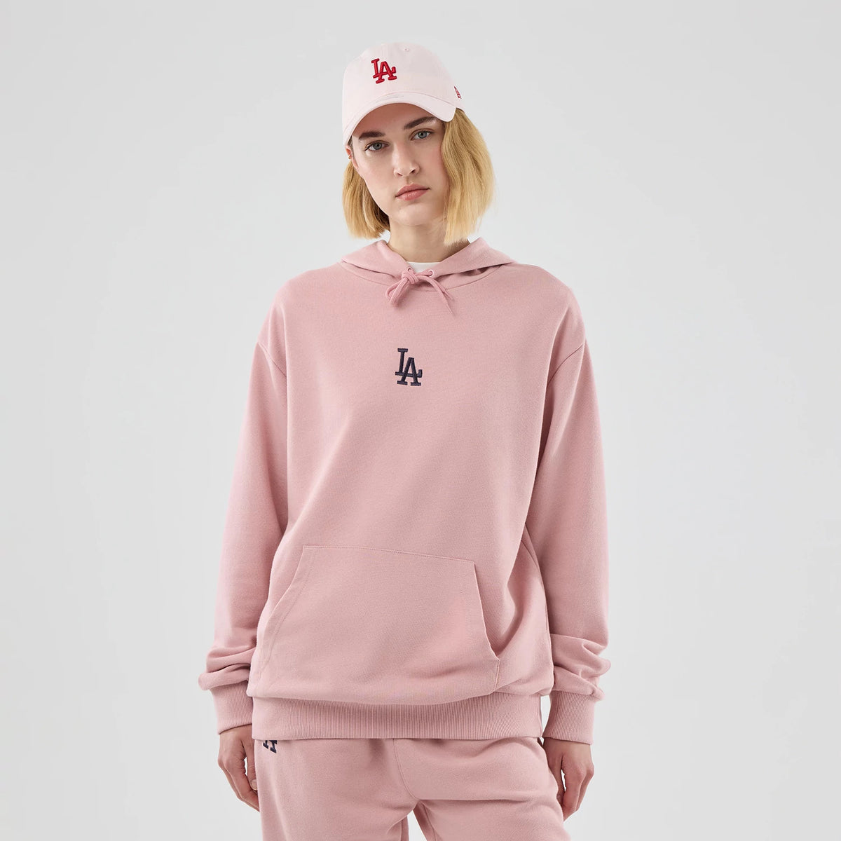 The model is wearing this MLB Midi League Essential LA Dodgers Oversized Pullover Hoodie in pastel pink. 4