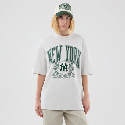 New Era New York Yankees MLB Arch Graphic Pastel Grey Oversized T-Shirt, front view on a model with matching cap, featuring large green New York lettering across the chest, an embroidered Yankees logo below it, and short sleeves.