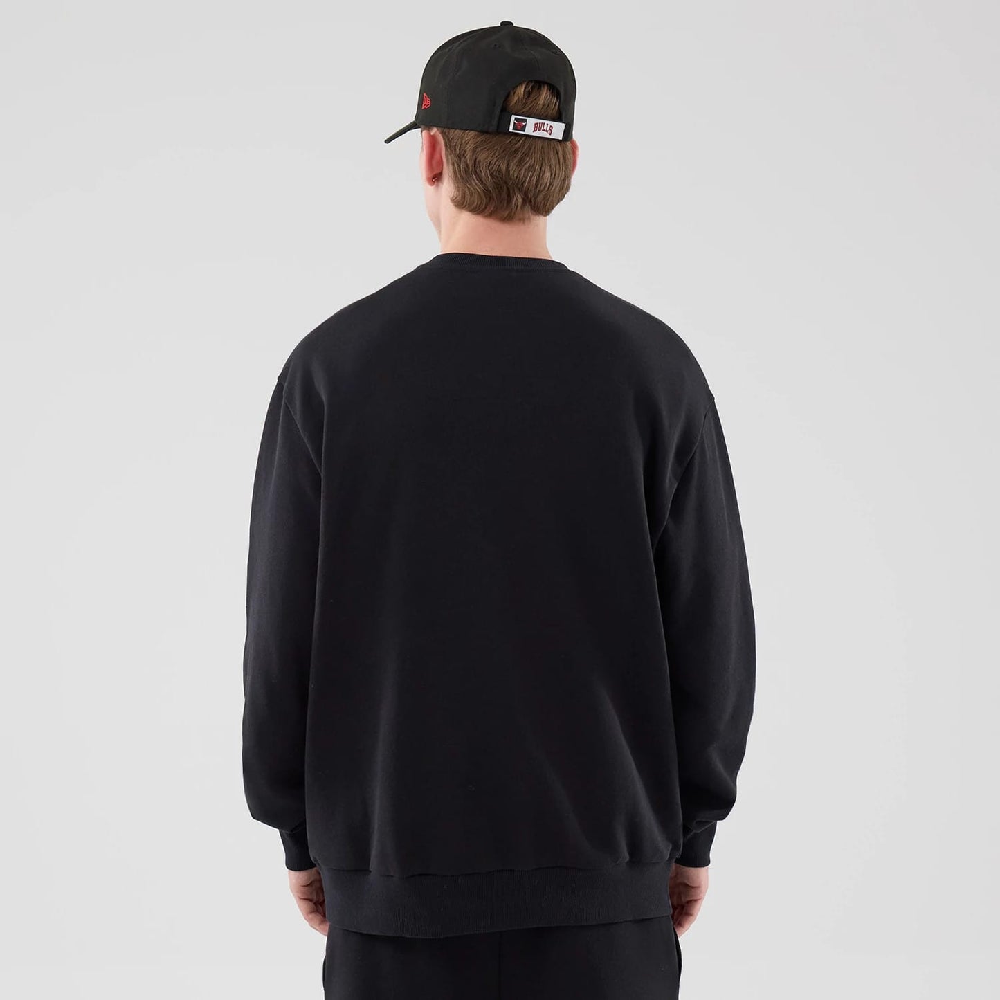 The model is wearing this NBA League Essential Chicago Bulls Oversized Crew Neck Sweater in black. 2