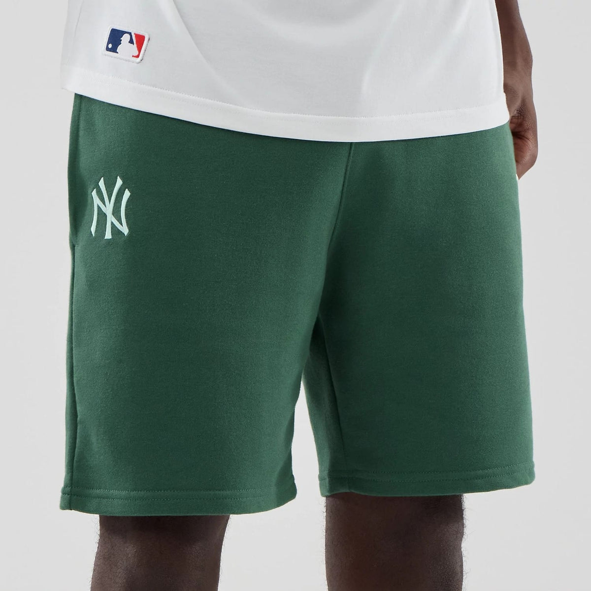 The model is wearing these MLB Midi League Essential New York Yankees Oversized Shorts in dark green. 6