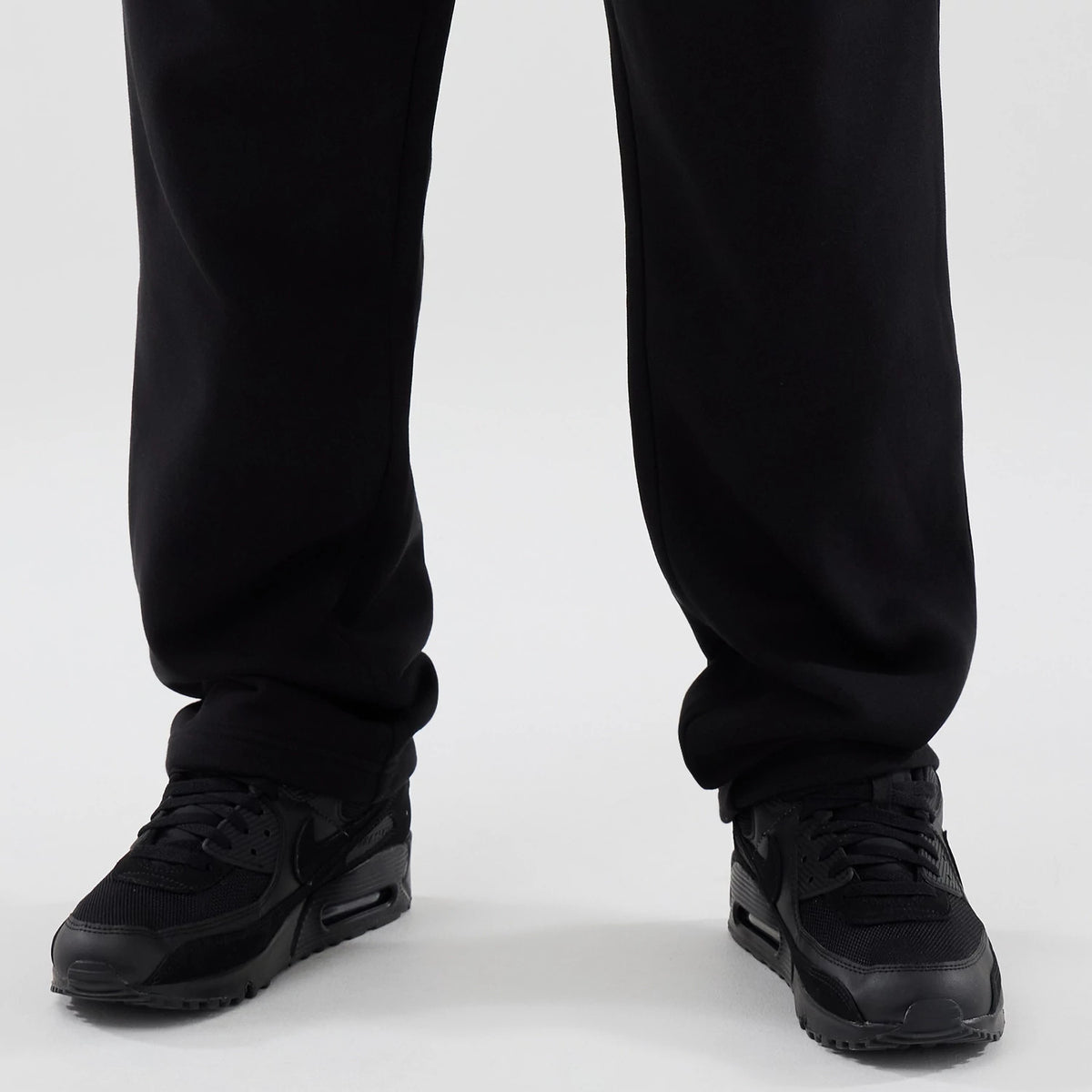 New Era Tech Reflective Black Straight Leg Joggers, close-up front view showing the lower legs with a relaxed fit and a black fabric, worn with black trainers for a and contemporary look.