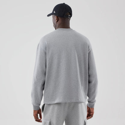 New Era Grey Oversized Crew Neck Sweater, back view on a model wearing matching grey sweatpants and a black cap with the New Era flag logo on the left side, highlighting the sweater’s simple design and relaxed fit.