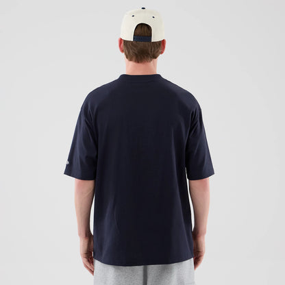 New Era New York Yankees MLB Arch Graphic Navy Oversized T-Shirt, back view on a model wearing a light cap and grey shorts, showing the plain navy back with a loose fit and a small embroidered New Era logo on the left sleeve.