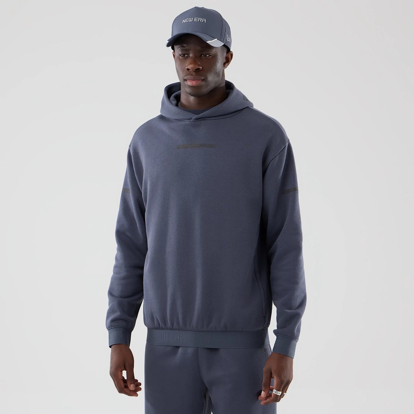 The model is wearing this New Era Tech Oversized Pullover Hoodie in grey. 1