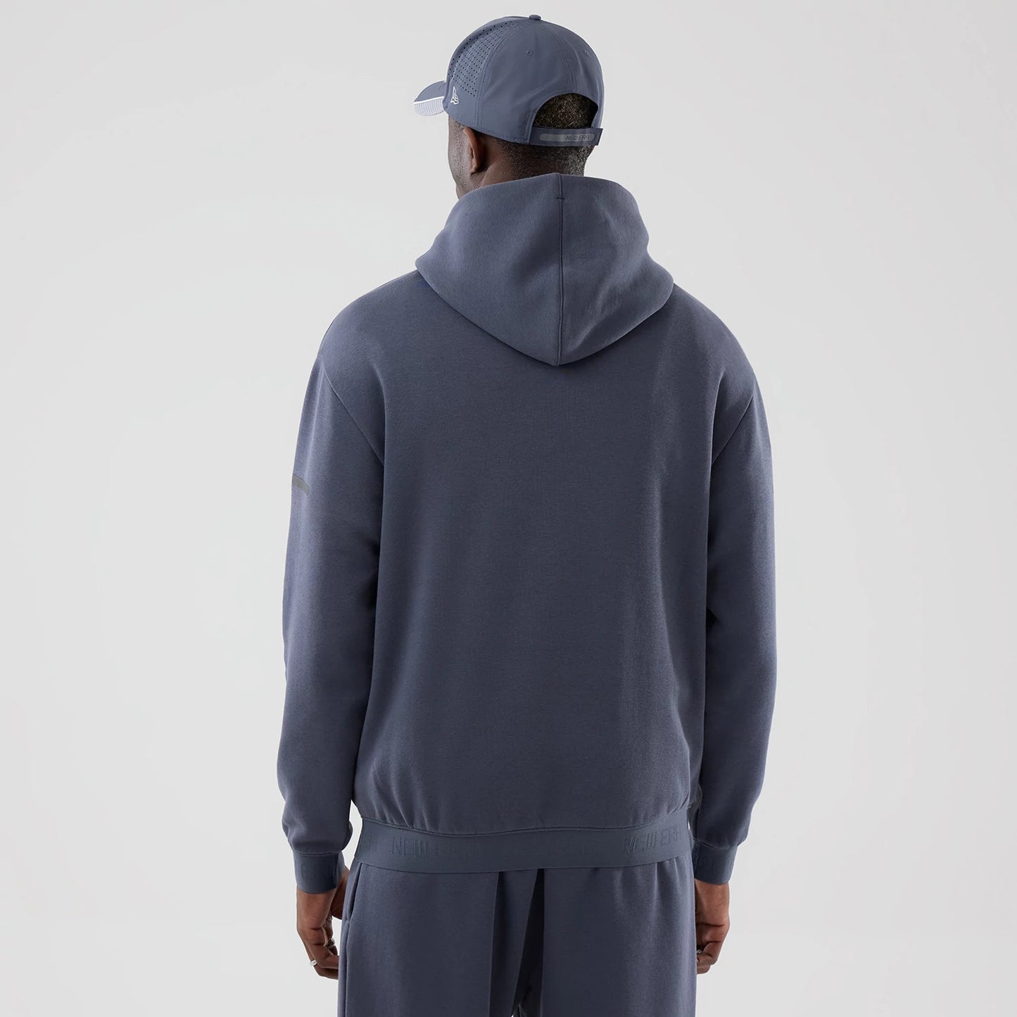 The model is wearing this New Era Tech Oversized Pullover Hoodie in grey. 2