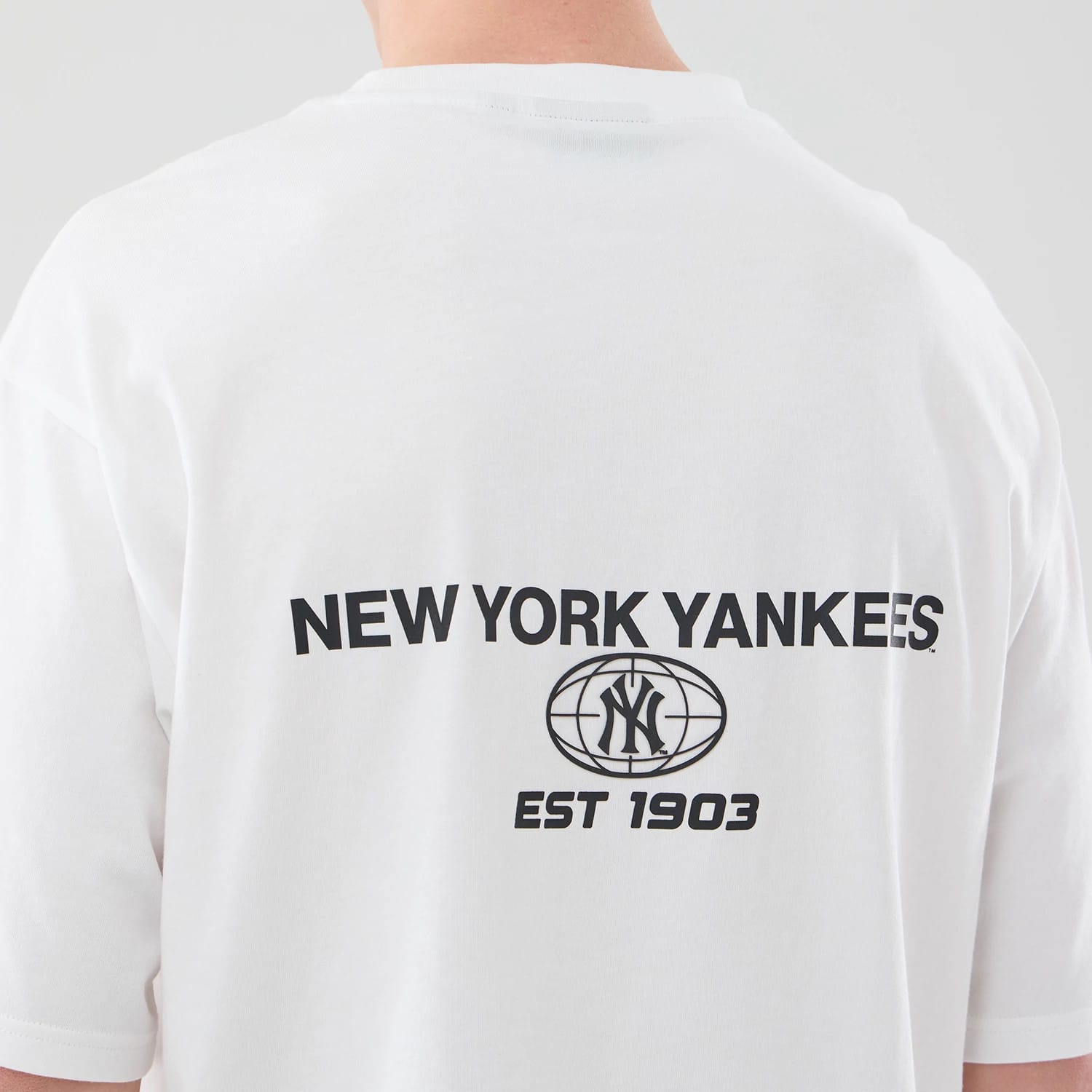 The model is wearing this MLB Logo Graphic New York Yankees Oversized T-Shirt in white. 7