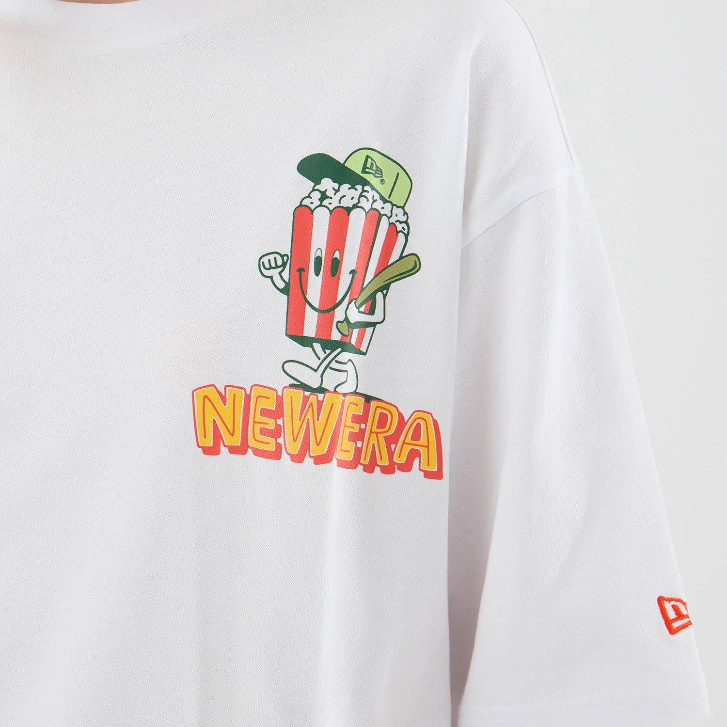 The model is wearing this New Era Baseball Popcorn Graphic Oversized T-Shirt in white. 6