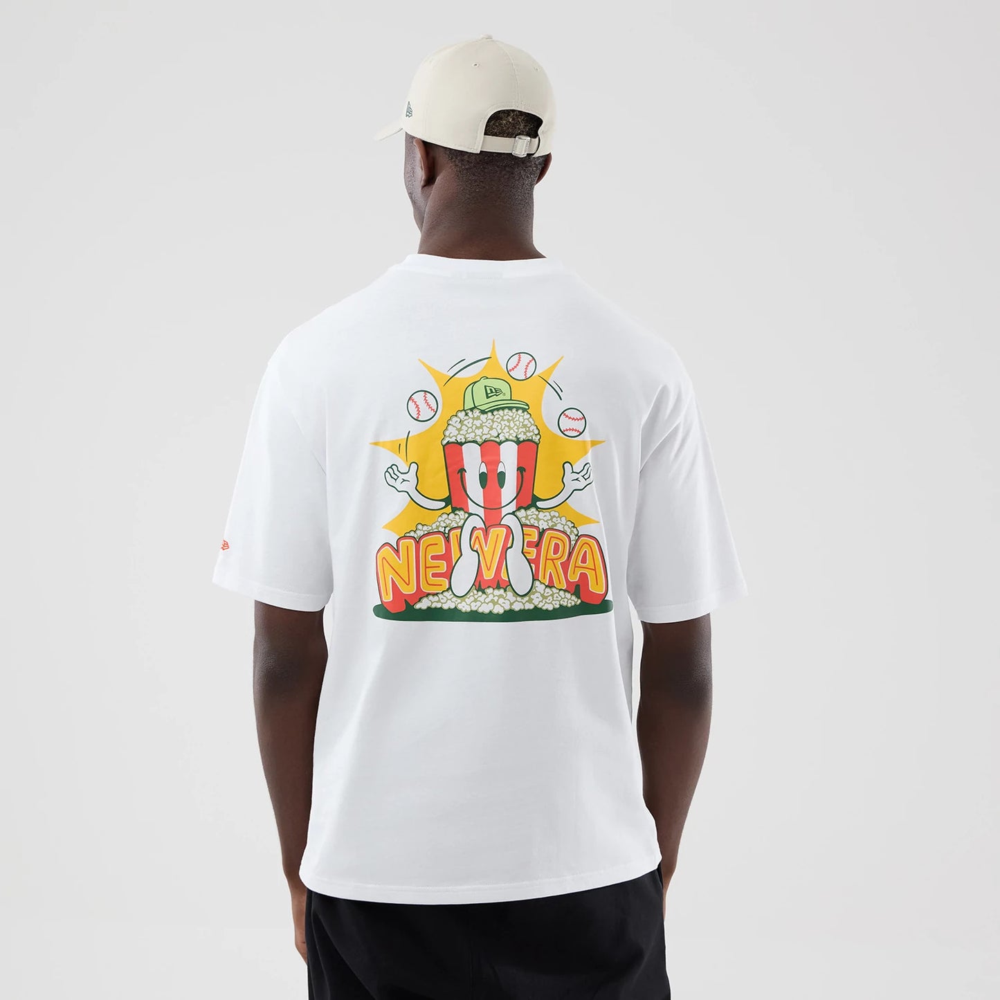 The model is wearing this New Era Baseball Popcorn Graphic Oversized T-Shirt in white. 2