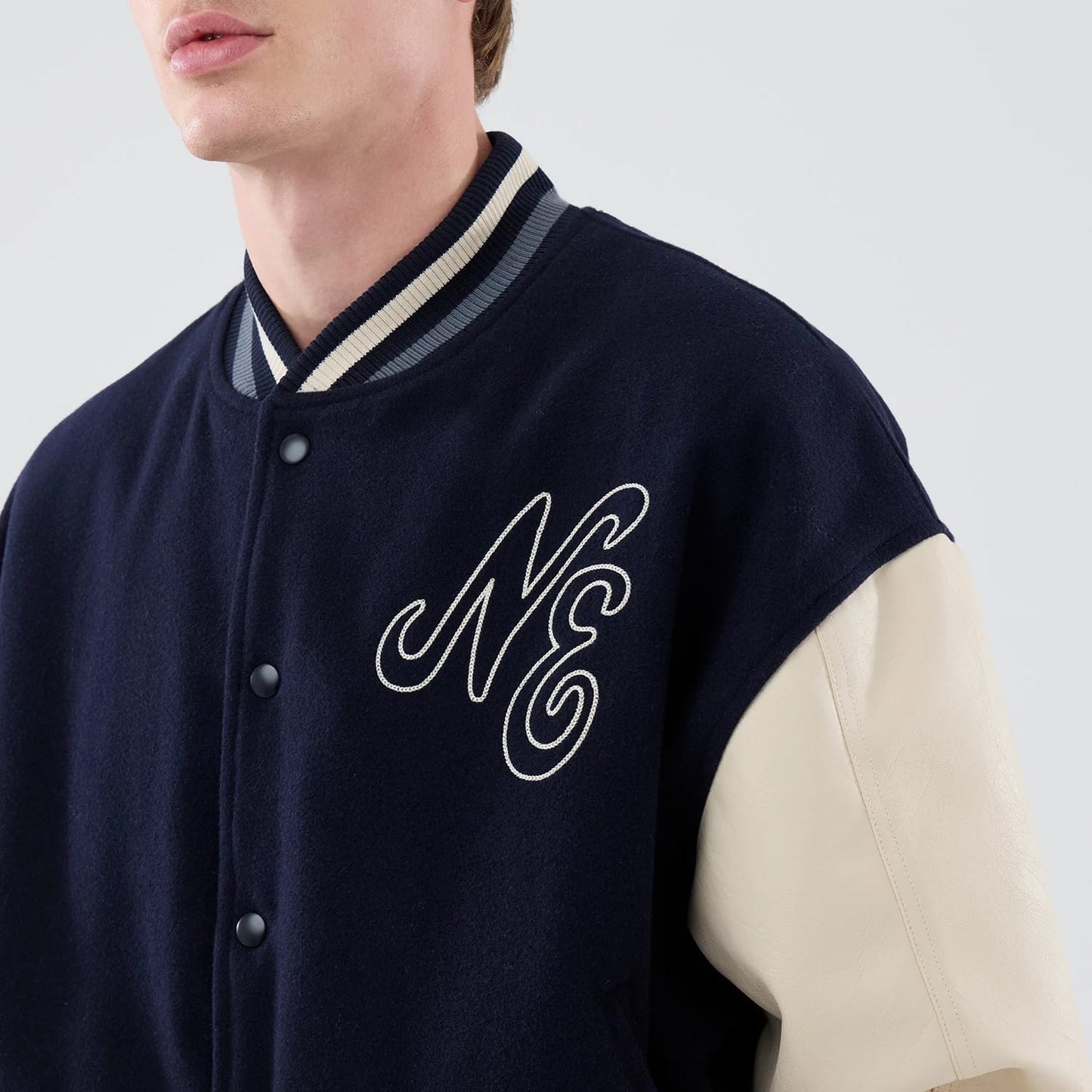 The model is wearing this New Era Oversized Varsity Jacket in navy. 5