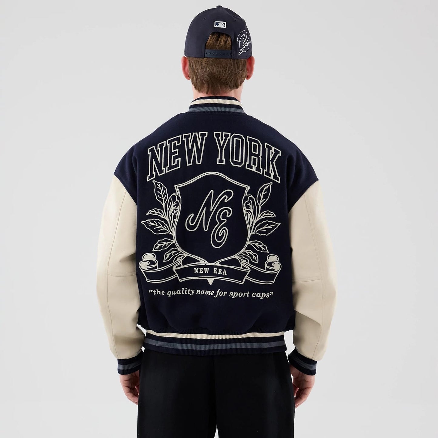 The model is wearing this New Era Oversized Varsity Jacket in navy. 2