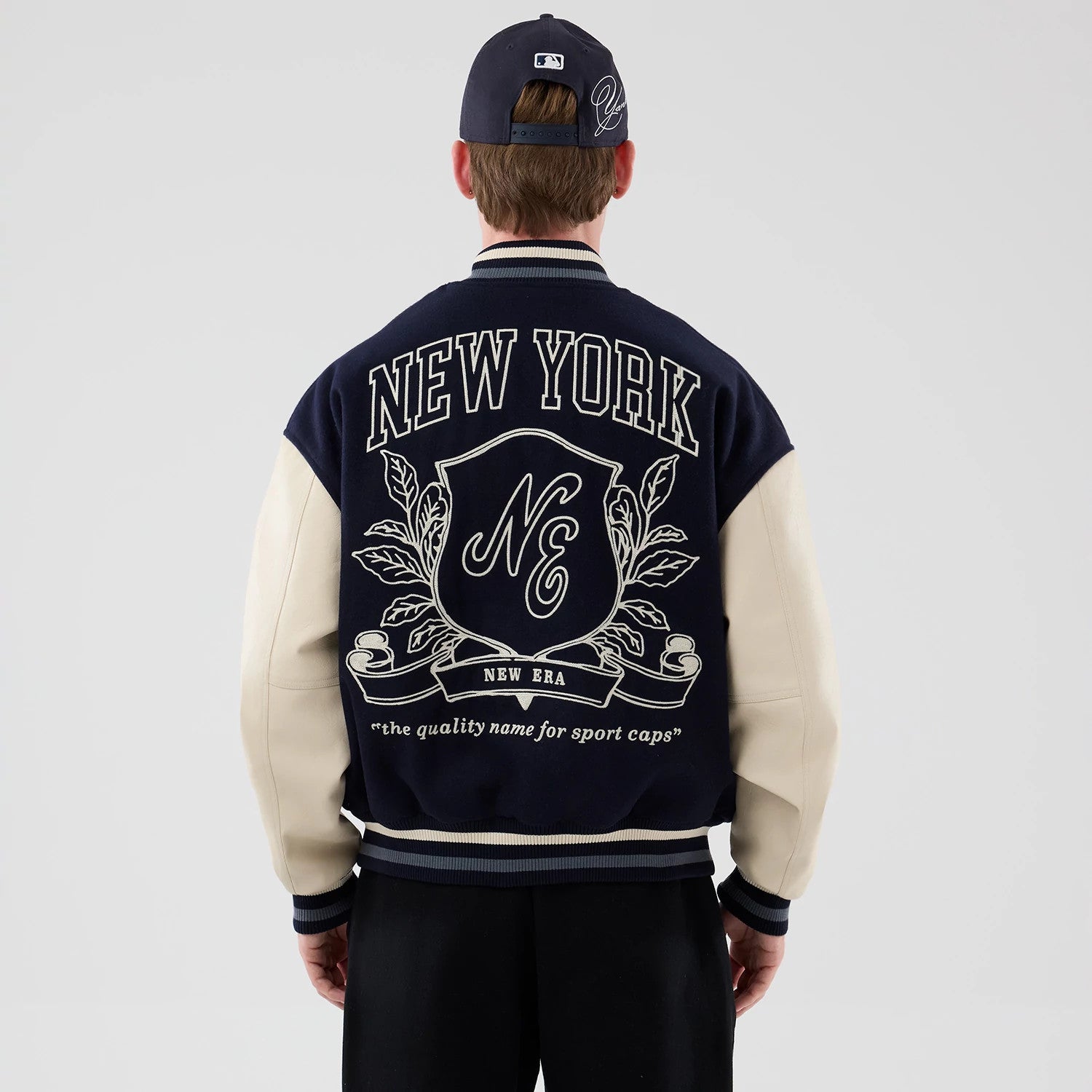 The model is wearing this New Era Oversized Varsity Jacket in navy. 2