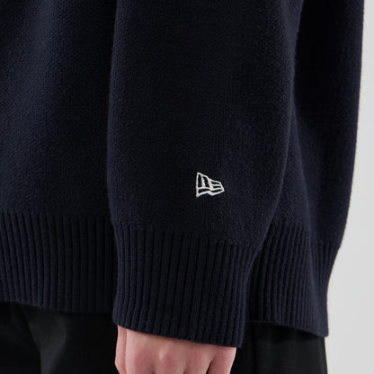 The model is wearing this New Era Knit Script Knitted Sweater in navy. 7