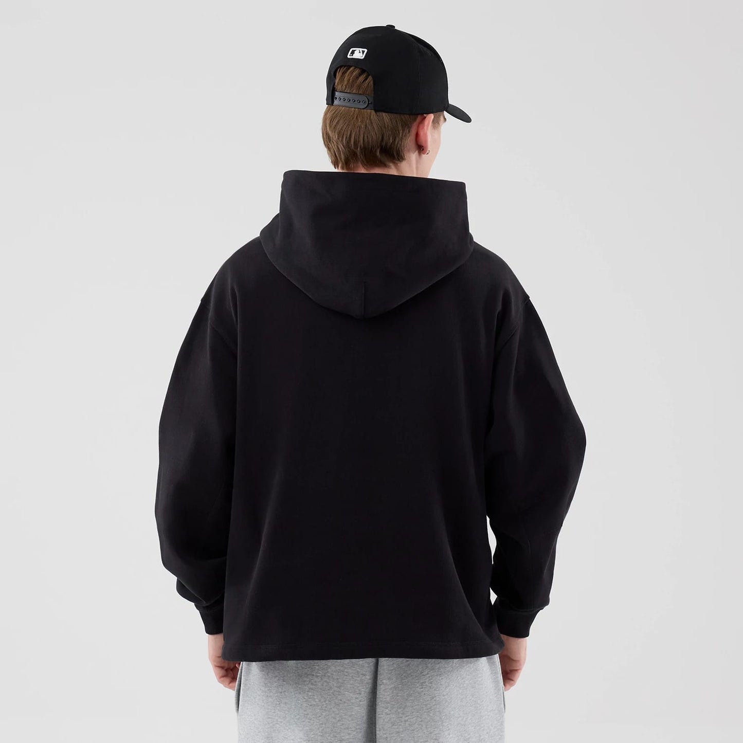 The model is wearing this New Era Open Hem Pullover Hoodie in black. 2