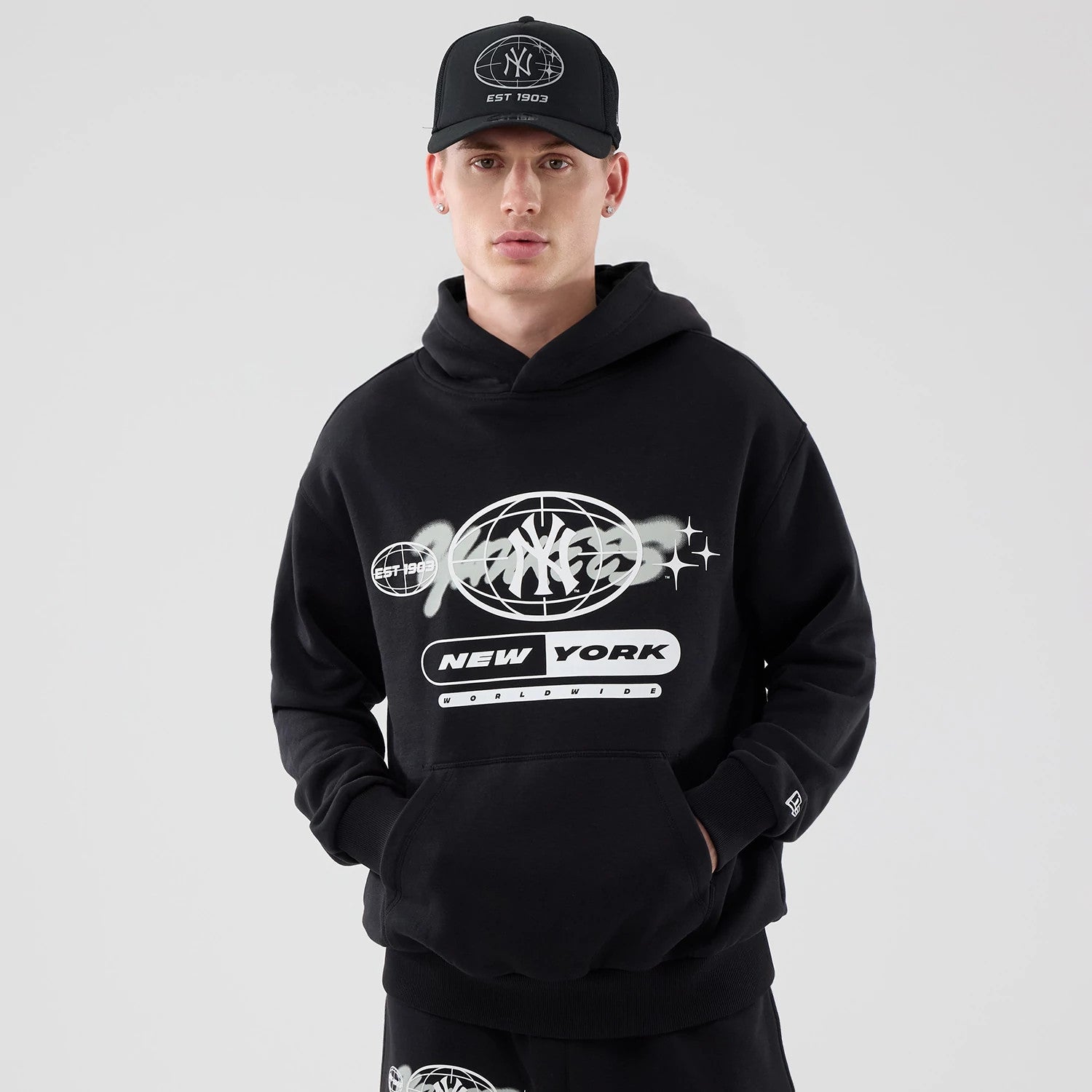 The model is wearing this MLB Logo Graphic New York Yankees Oversized Pullover Hoodie in black. 1