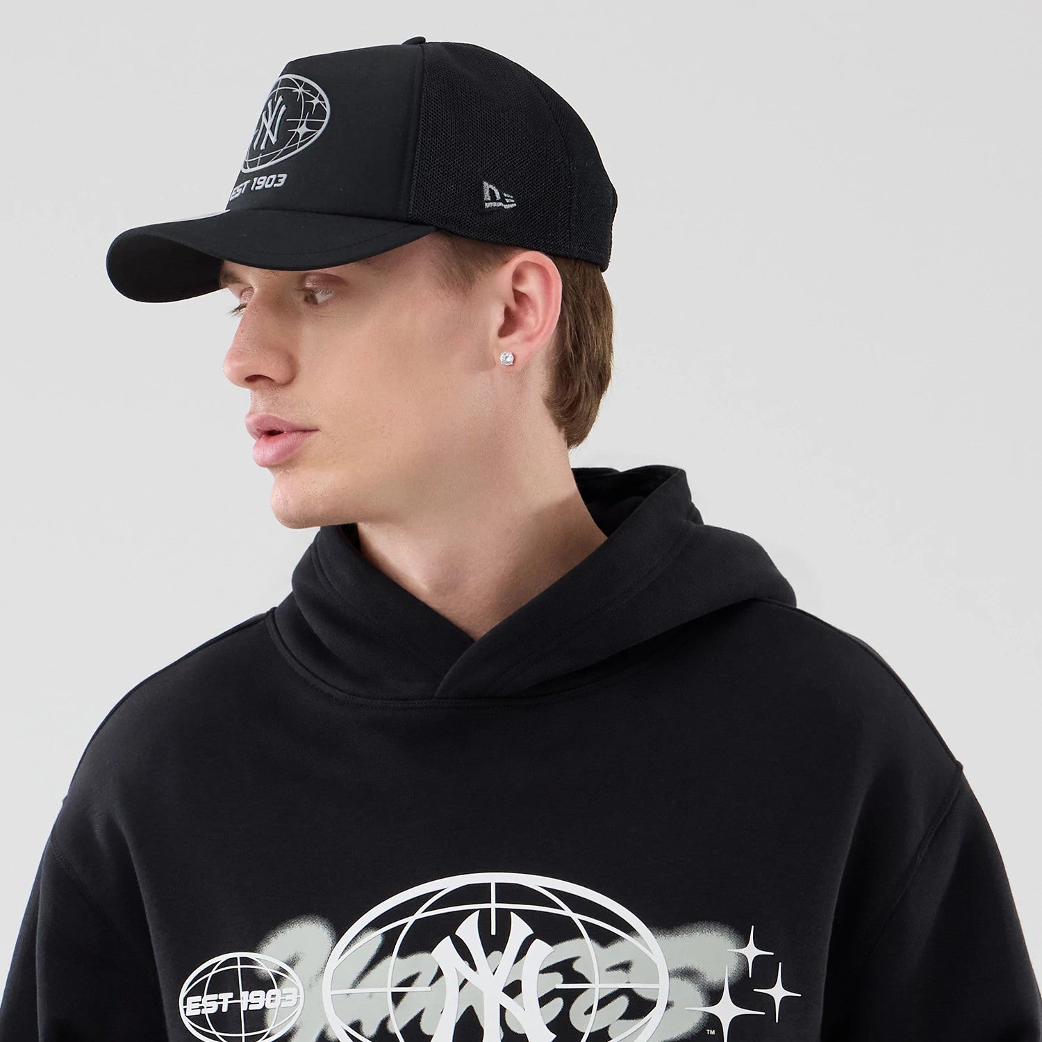 The model is wearing this MLB Logo Graphic New York Yankees Oversized Pullover Hoodie in black. 4