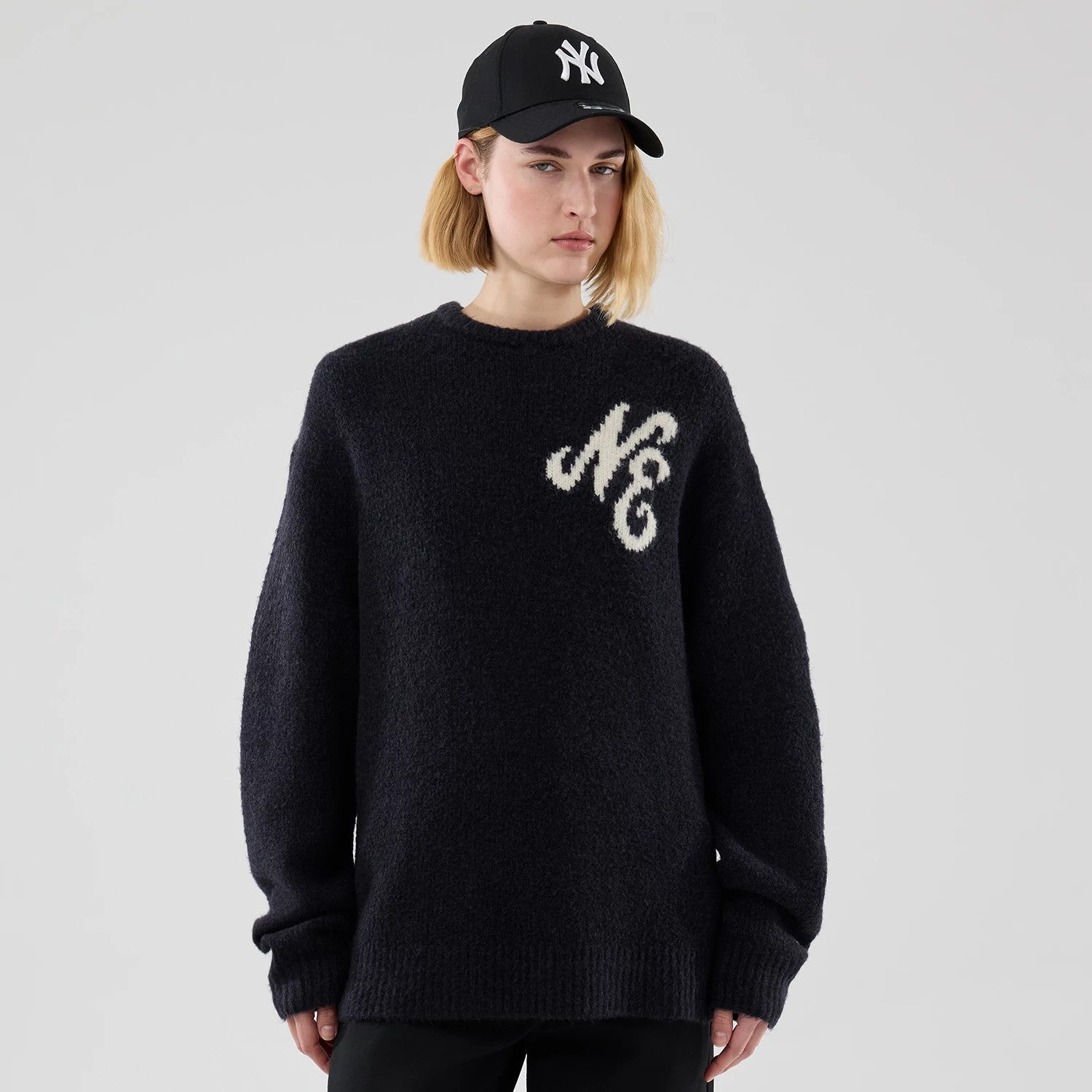 The model is wearing this New Era Knit Heritage Knitted Sweater in navy. 4