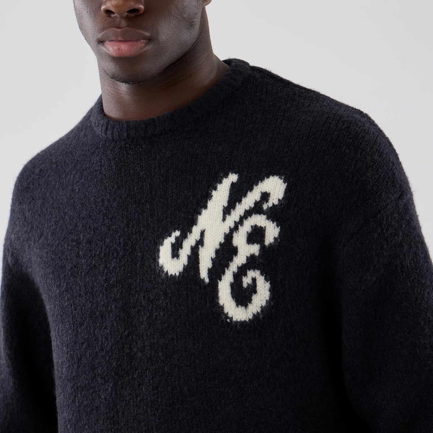 The model is wearing this New Era Knit Heritage Knitted Sweater in navy. 5