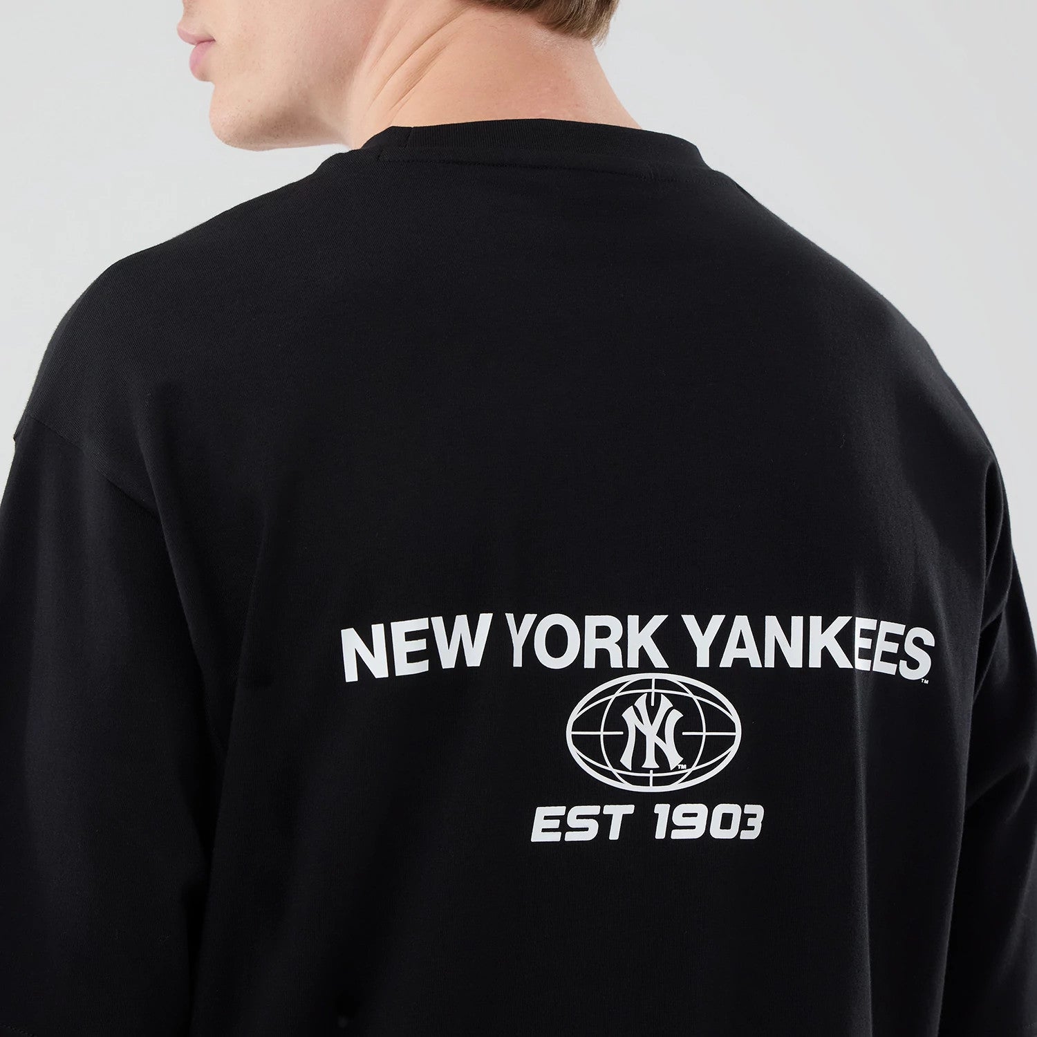 The model is wearing this MLB Logo Graphic New York Yankees Oversized T-Shirt in black. 5