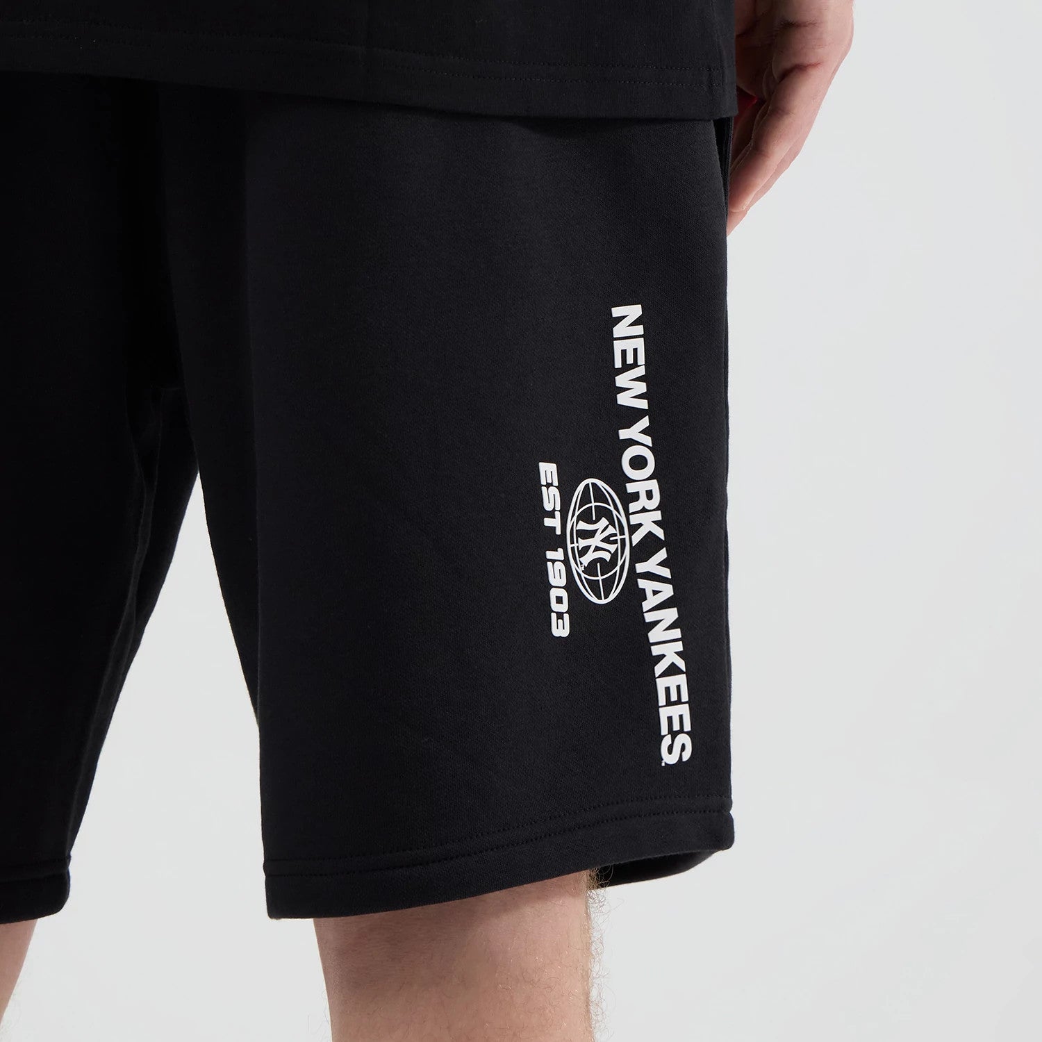 The model is wearing these MLB Logo Graphic New York Yankees Oversized Shorts in black. 6