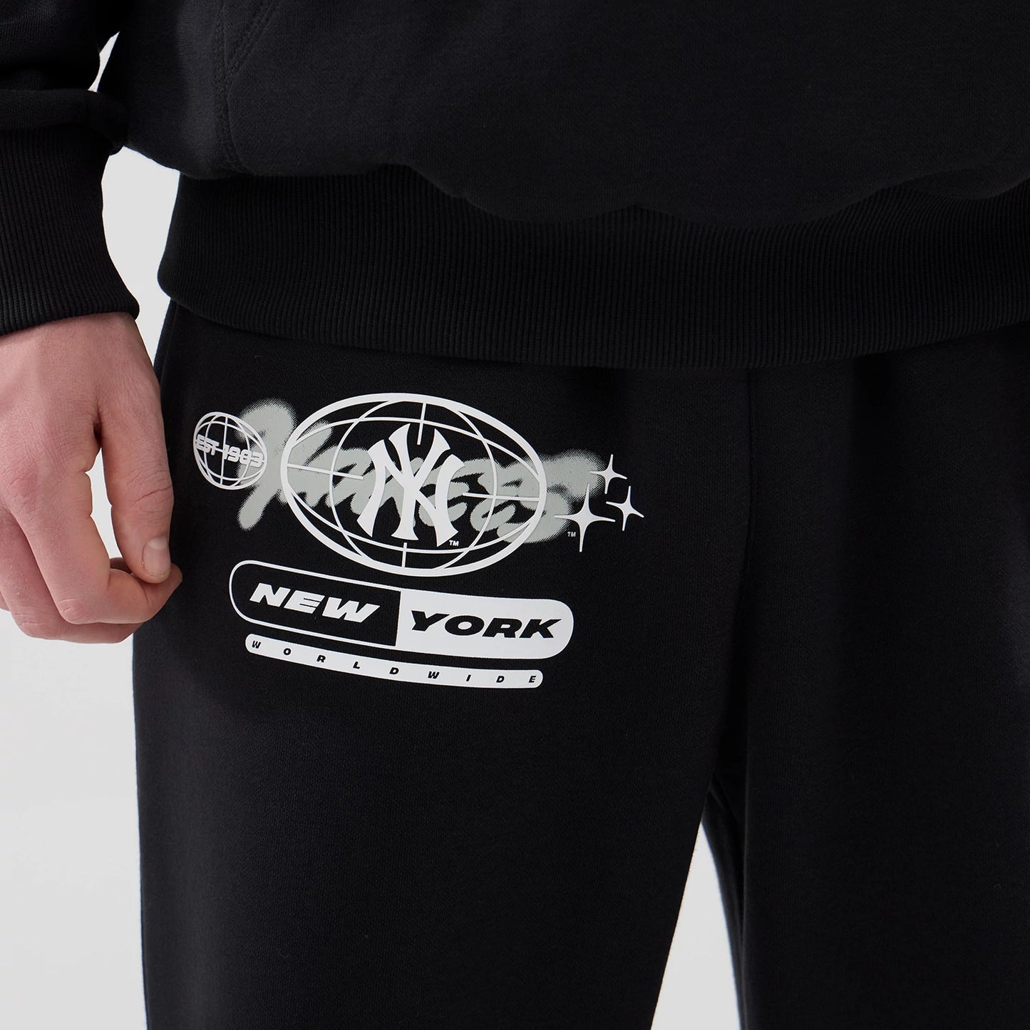 The model is wearing these MLB Logo Graphic New York Yankees Straight Leg Joggers in black. 4