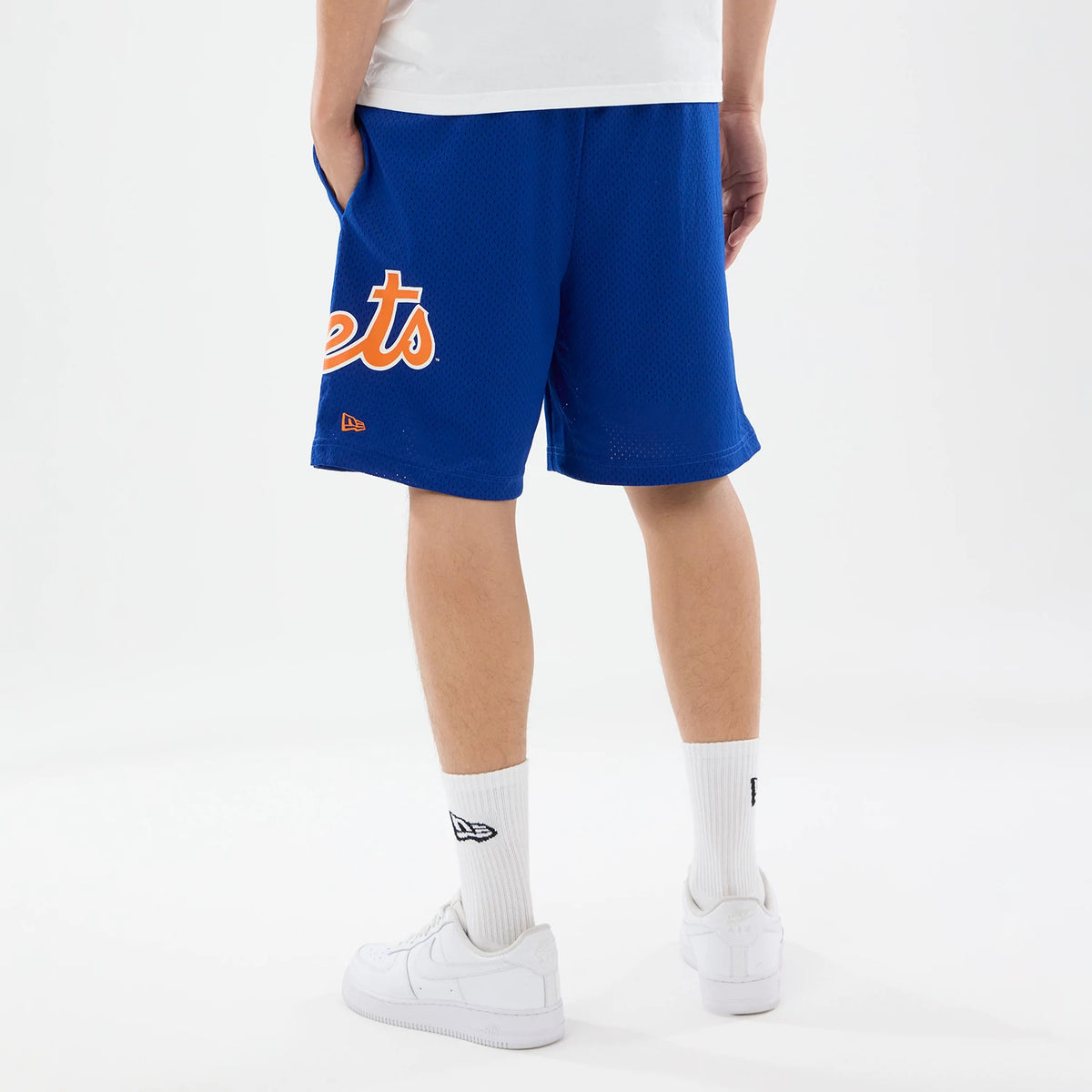 New Era New York Mets MLB Evergreen Blue Shorts, back view on-model showing broad Mets lettering in orange and white on the left leg, a small embroidered New Era logo below, and the blue colour extending across the shorts with athletic styling.