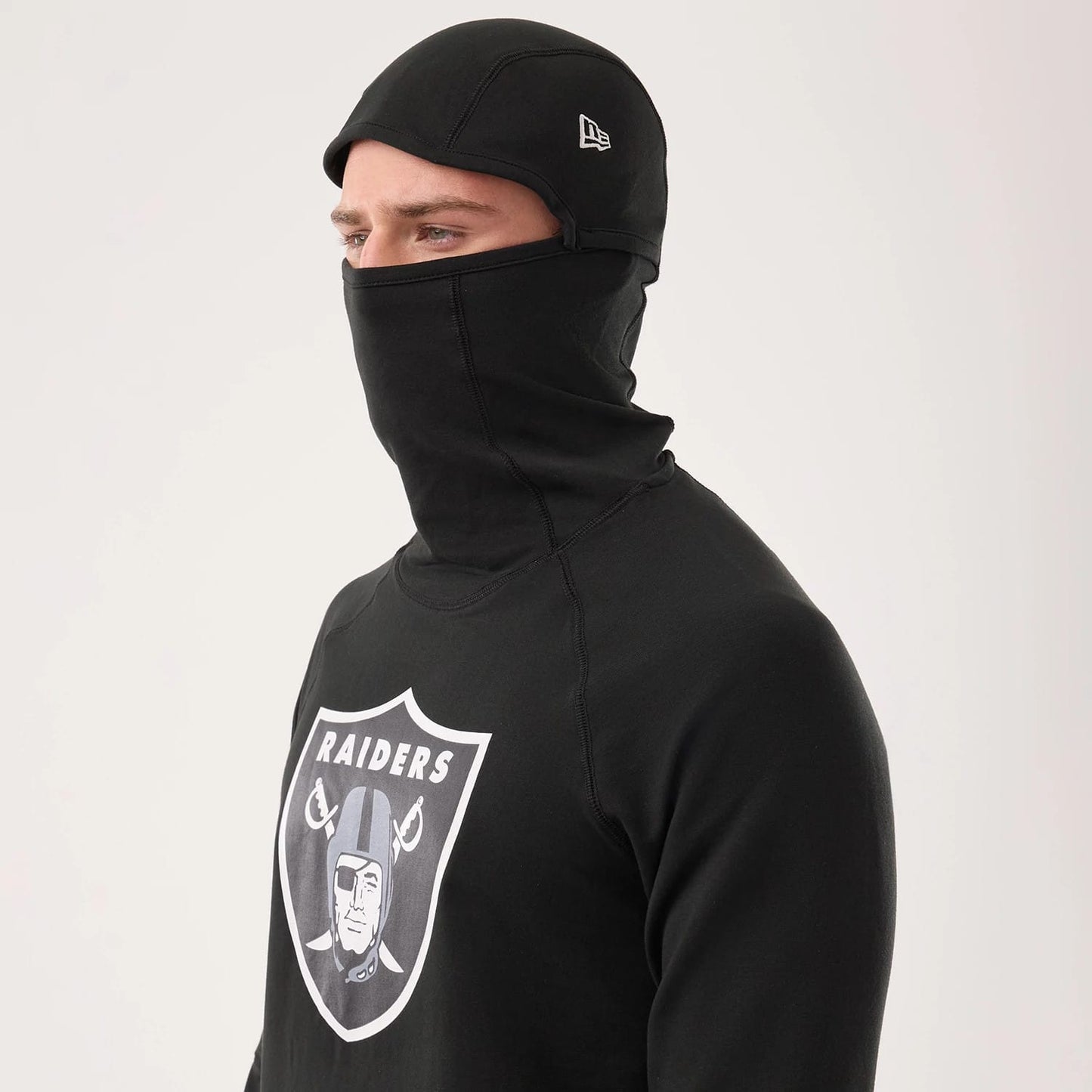 The model is wearing this NFL Sideline 2026 Las Vegas Raiders Balaclava Hoodie in black. 3