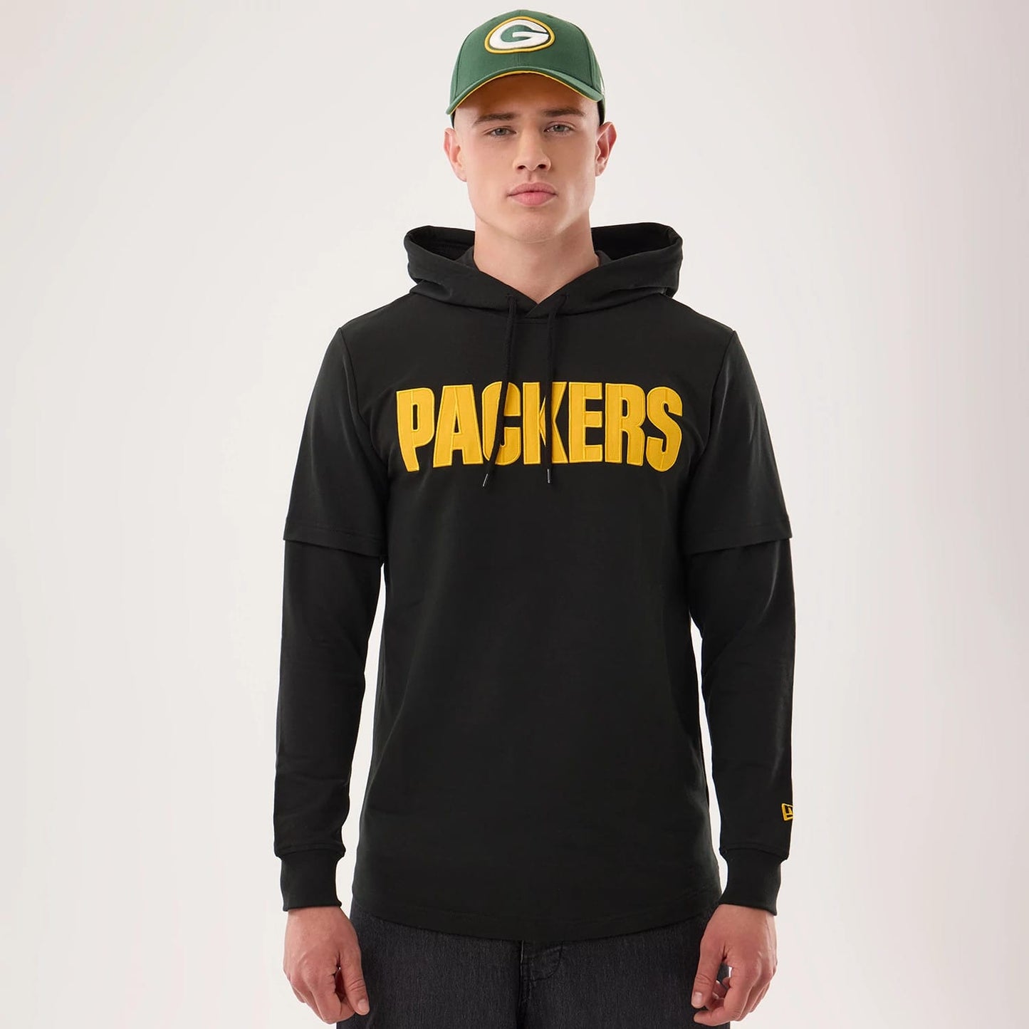 The model is wearing this NFL Sideline 2026 Green Bay Packers Double Sleeve Hoodie in black. 1