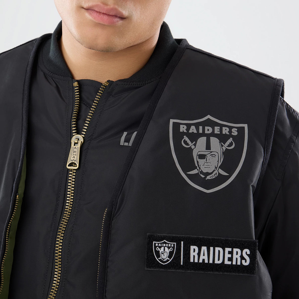 The model is wearing this NFL X Alpha Las Vegas Raiders Bomber Jacket & Tactical Vest in black. 6