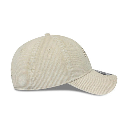 New Era Washed Cord Cream 9TWENTY Adjustable Cap, side view showing the textured cream corduroy fabric on the structured crown and curved visor, with embroidered New Era flag logo on the left side panel and 9TWENTY size sticker on the visor.