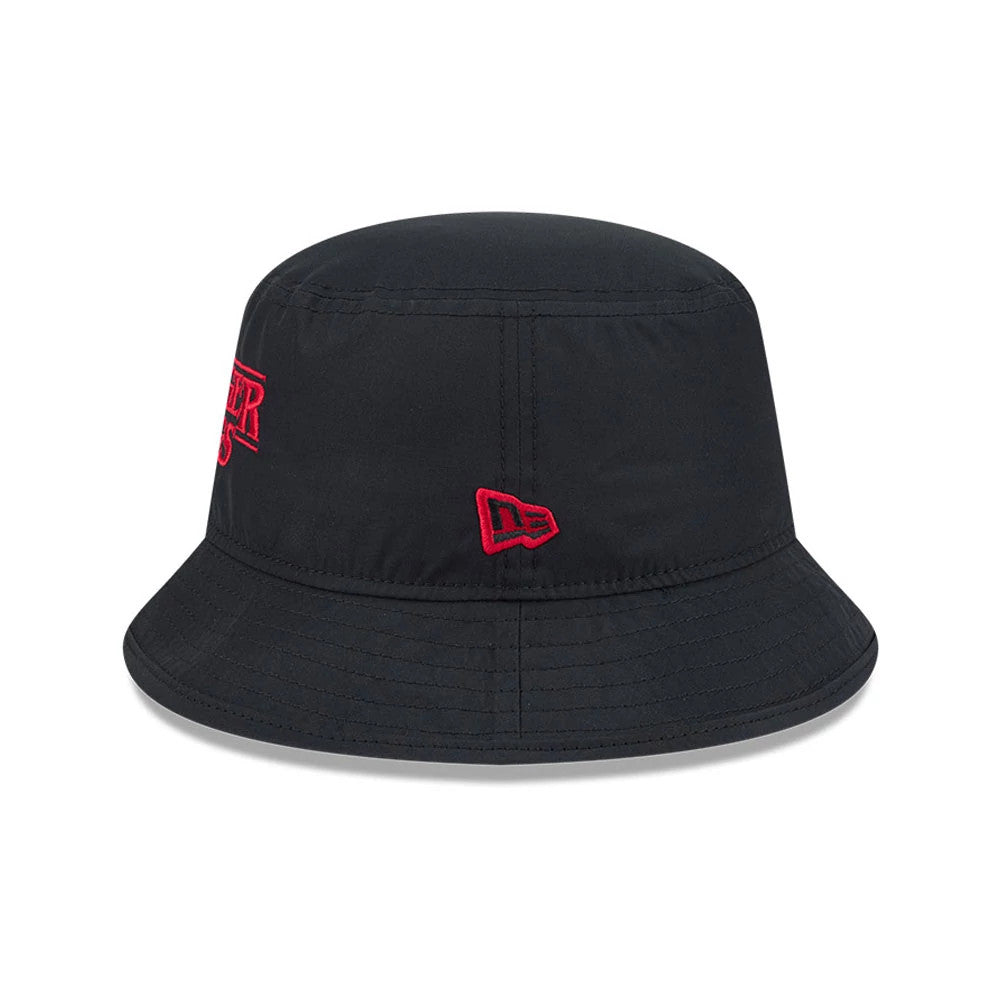 New Era Netflix Stranger Things Black Bucket Hat, three-quarter view showing the red embroidered Stranger Things logo on the side of the black crown, with a red embroidered New Era flag logo beside it and a downward-sloping black visor.