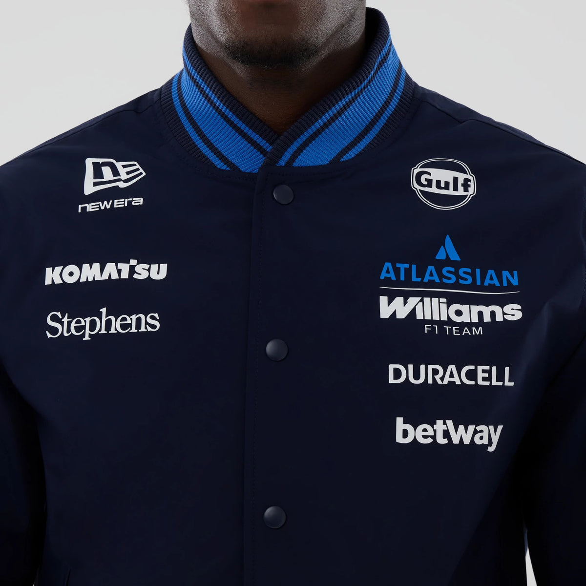 New Era Williams Navy Varsity Jacket, front view showing multiple sponsor logos including Gulf, Atlassian, and Williams F1 Team embroidered on the chest, a striped collar, and the New Era logo embroidered on the shoulder.
