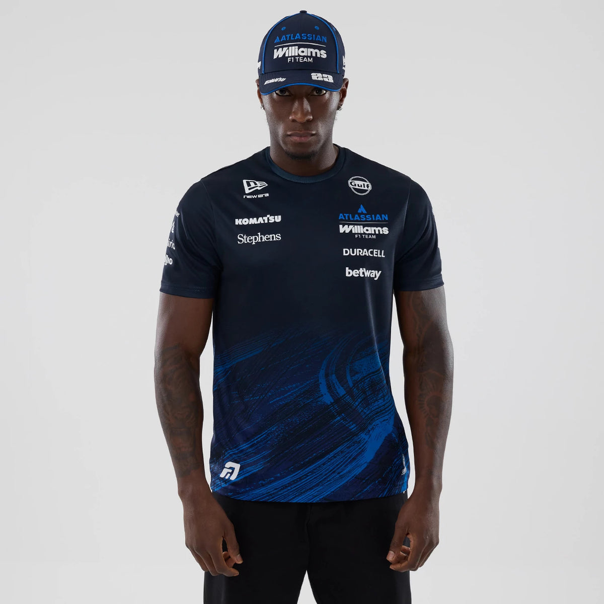 New Era Williams Alex Albon Navy Tech T-shirt, front view on a model with a matching cap, displaying multiple white logos including Williams on the chest, a New Era embroidered logo on the upper right.