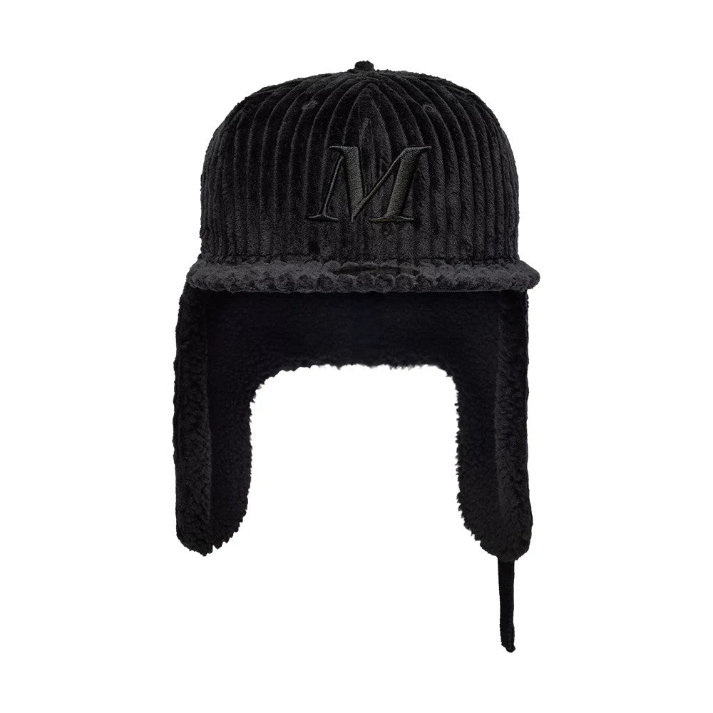 Mains X New Era Cord Black Dogear 59FIFTY Fitted Cap, front view showing a large black embroidered letter M on the ridged corduroy fabric crown, with soft extended earflaps in matching black and a flat visor.