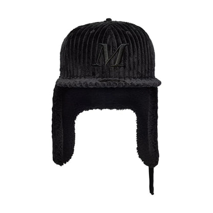Mains X New Era Cord Black Dogear 59FIFTY Fitted Cap, front view showing a large black embroidered letter M on the ridged corduroy fabric crown, with soft extended earflaps in matching black and a flat visor.